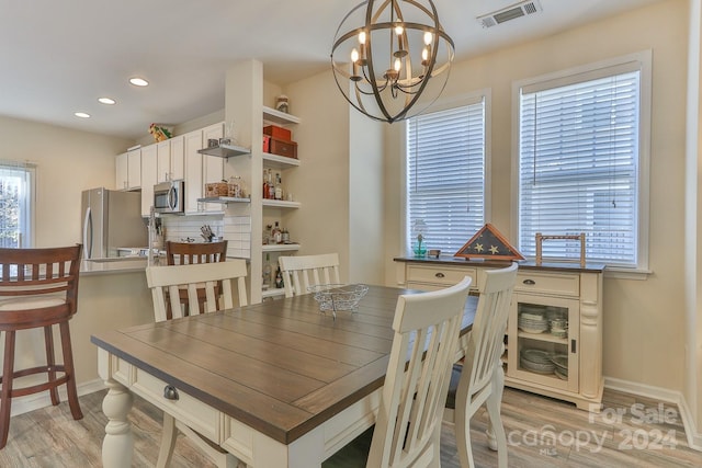 dining room with light hardwood / wood-style floors and an inviting chandelier