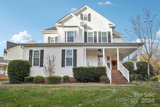 view of front facade with ceiling fan, covered porch, and a front yard