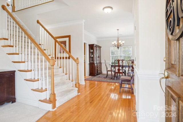 foyer with a chandelier, hardwood / wood-style flooring, and ornamental molding