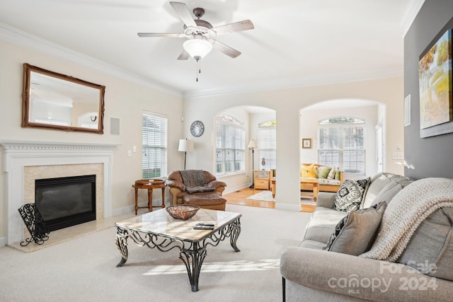 living room with ceiling fan, ornamental molding, light carpet, and a high end fireplace