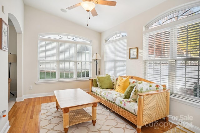 living area with ceiling fan, lofted ceiling, and light wood-type flooring