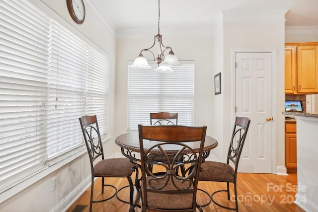 dining area with crown molding, light hardwood / wood-style flooring, and a chandelier