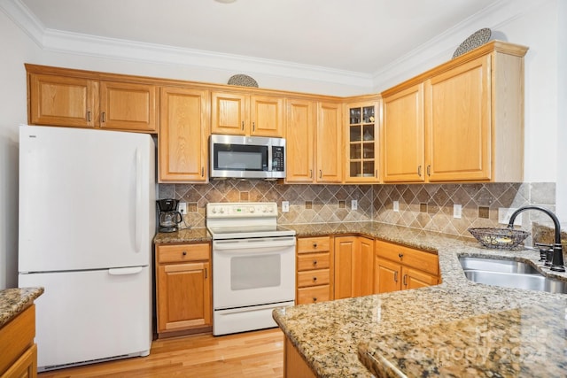 kitchen with light stone countertops, white appliances, sink, and light hardwood / wood-style flooring