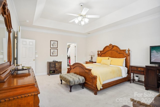 carpeted bedroom featuring a raised ceiling, ceiling fan, crown molding, and a spacious closet