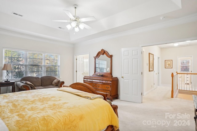 bedroom with a raised ceiling, ceiling fan, light carpet, and ornamental molding