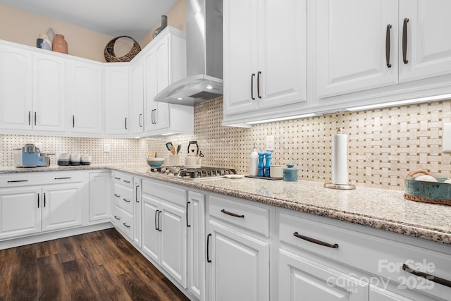 kitchen featuring decorative backsplash, wall chimney exhaust hood, dark hardwood / wood-style floors, white cabinetry, and stainless steel gas stovetop