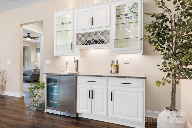 bar featuring dark wood-type flooring, white cabinets, beverage cooler, and stone countertops