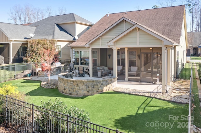 back of house featuring a lawn, a sunroom, a patio, and an outdoor kitchen