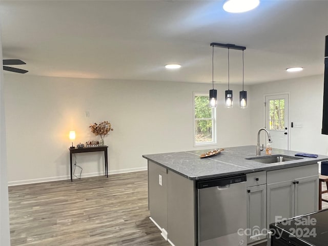 kitchen featuring dishwasher, a kitchen island with sink, sink, hanging light fixtures, and wood-type flooring