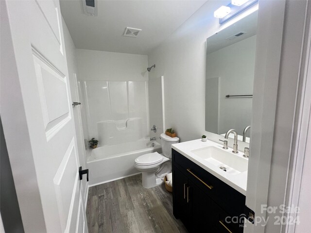 full bathroom featuring toilet, wood-type flooring, vanity, and bathing tub / shower combination