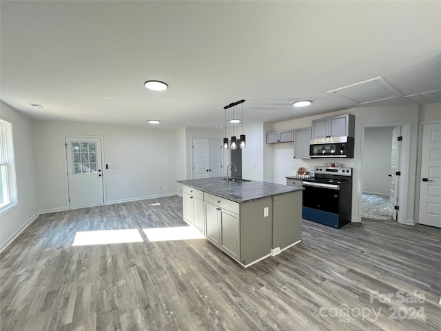 kitchen with sink, gray cabinets, light wood-type flooring, an island with sink, and appliances with stainless steel finishes