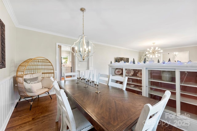 dining area with wainscoting, a chandelier, dark wood-style flooring, and ornamental molding