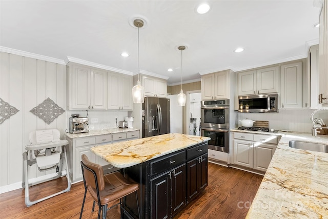 kitchen with a kitchen island, ornamental molding, decorative light fixtures, stainless steel appliances, and a sink