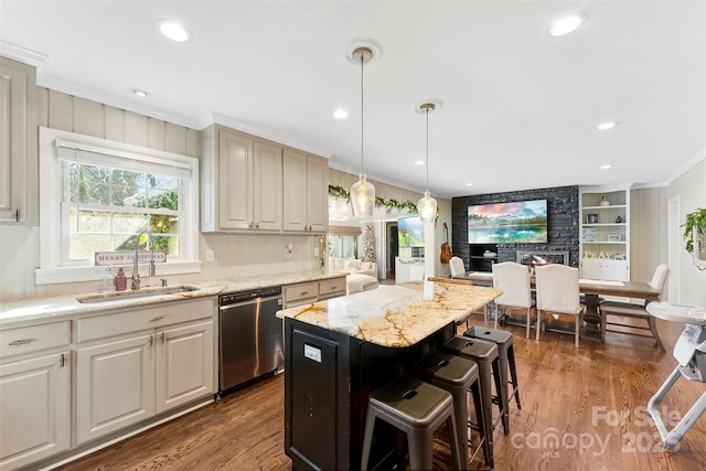 kitchen with stainless steel dishwasher, ornamental molding, a kitchen island, a sink, and light stone countertops