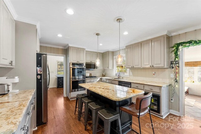 kitchen with light stone counters, stainless steel appliances, a kitchen island, ornamental molding, and a kitchen bar