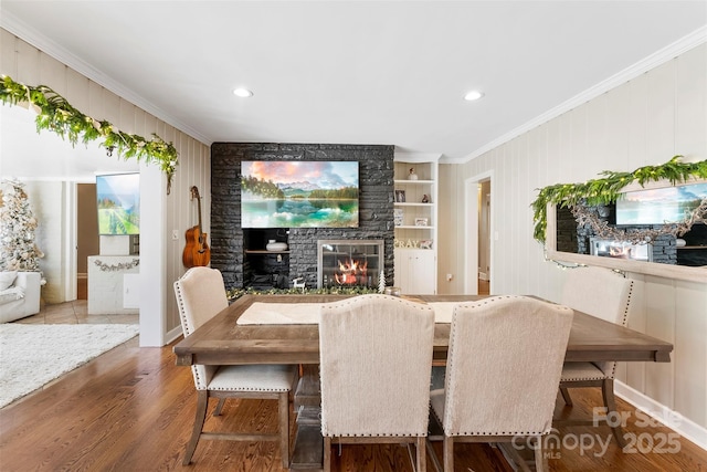 dining room with ornamental molding, a fireplace, wood finished floors, and built in shelves