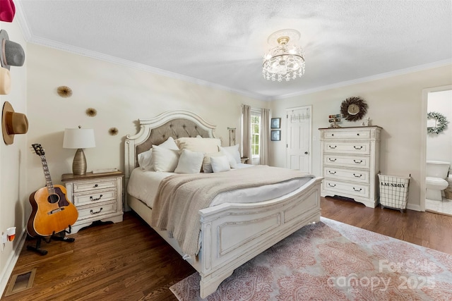 bedroom featuring visible vents, dark wood-style floors, ensuite bath, crown molding, and a chandelier