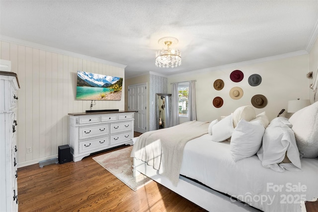 bedroom with ornamental molding, dark wood-type flooring, a textured ceiling, and a chandelier