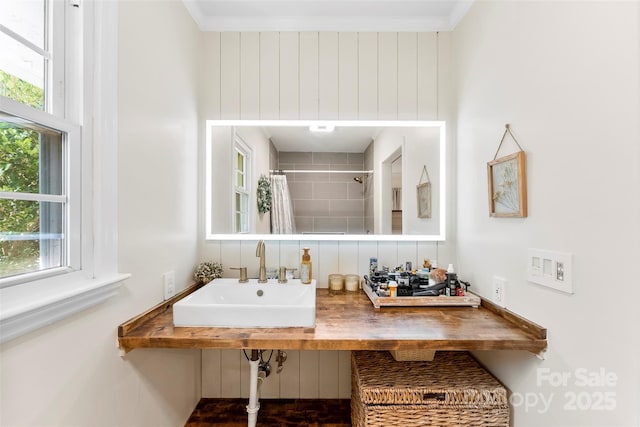 full bathroom with a tile shower, a sink, and crown molding