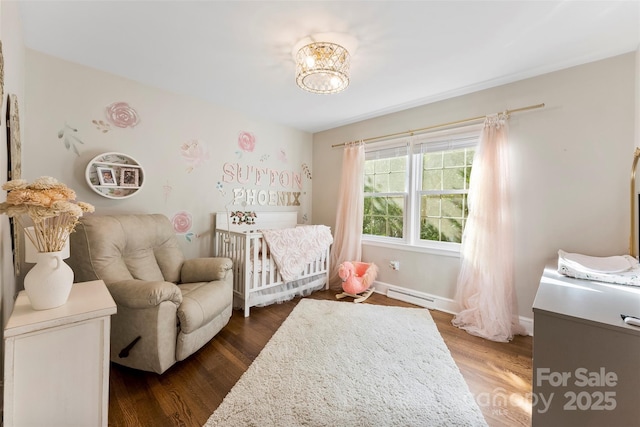 bedroom with baseboards, a baseboard radiator, dark wood-type flooring, a nursery area, and a chandelier