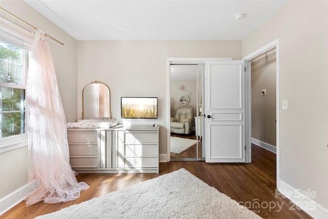 bedroom featuring dark wood-type flooring, a closet, and baseboards