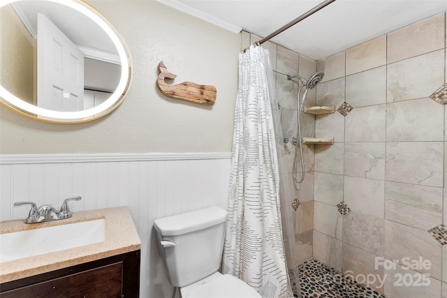 full bath with toilet, wainscoting, tiled shower, and vanity