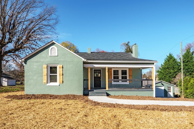 view of front facade featuring a porch, a shed, and a front lawn