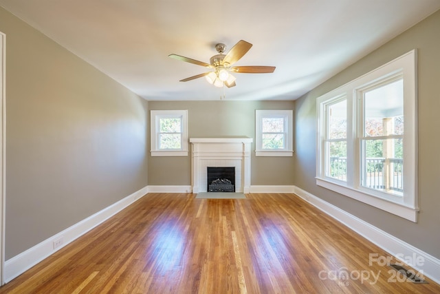 unfurnished living room featuring ceiling fan, light wood-type flooring, and a fireplace