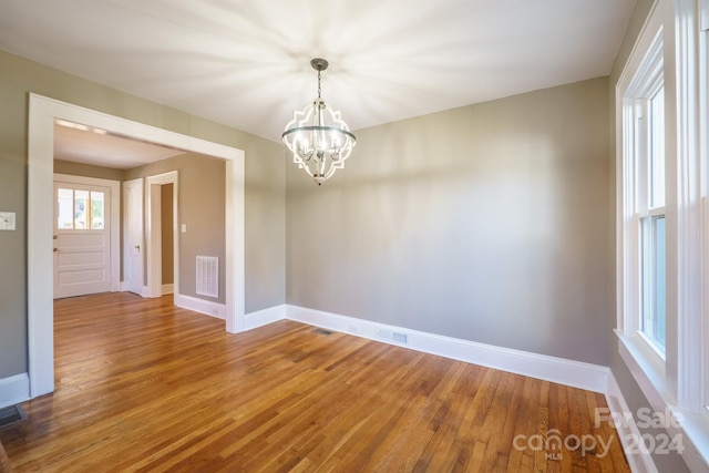 spare room with hardwood / wood-style floors and a chandelier