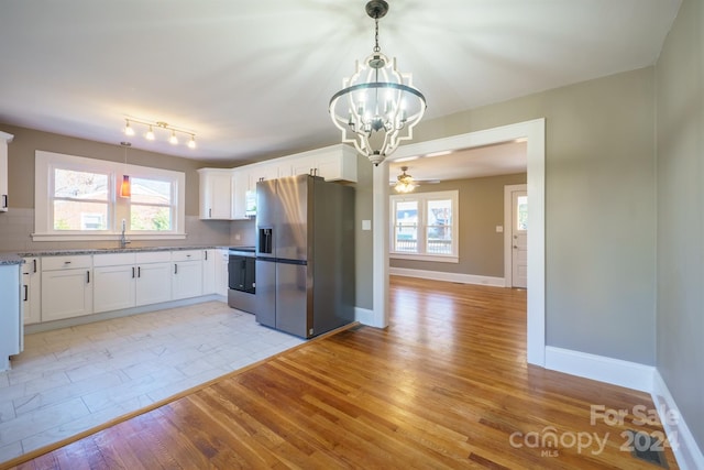 kitchen featuring light stone countertops, light hardwood / wood-style floors, white cabinets, ceiling fan with notable chandelier, and appliances with stainless steel finishes