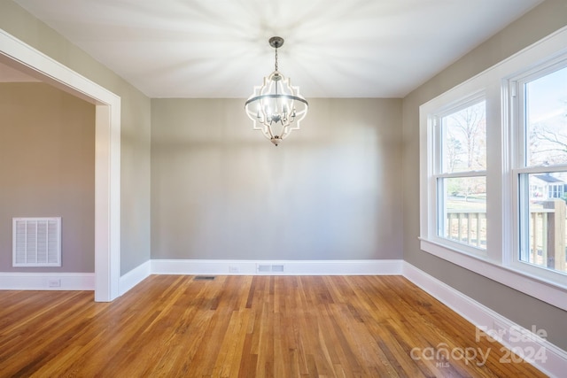 unfurnished room featuring hardwood / wood-style flooring and an inviting chandelier