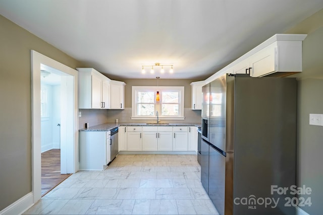 kitchen featuring light stone countertops, appliances with stainless steel finishes, tasteful backsplash, sink, and white cabinetry