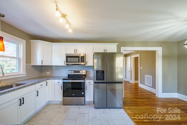 kitchen featuring backsplash, white cabinetry, and appliances with stainless steel finishes