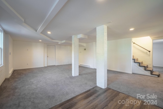 basement with a baseboard radiator and dark hardwood / wood-style floors