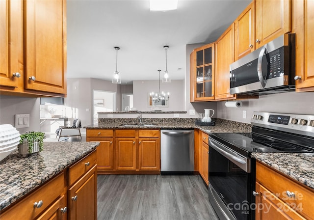 kitchen featuring dark stone counters, an inviting chandelier, sink, dark hardwood / wood-style floors, and appliances with stainless steel finishes