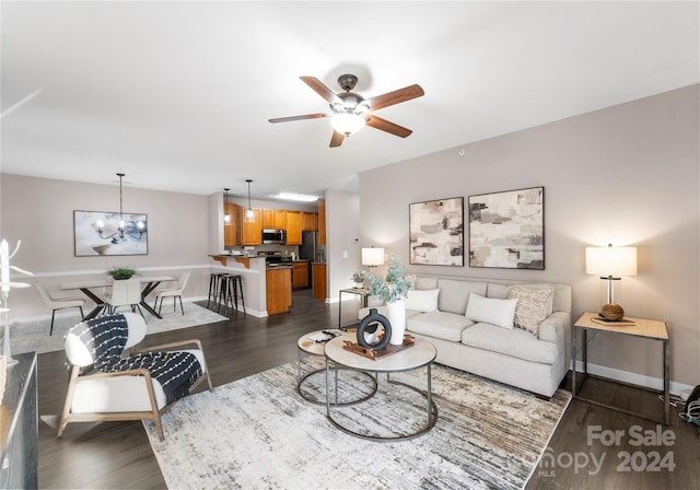 living room with dark hardwood / wood-style flooring and ceiling fan with notable chandelier