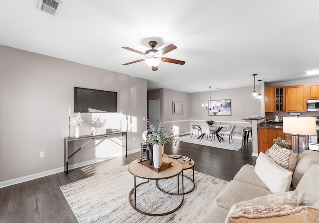 living room featuring ceiling fan with notable chandelier and dark hardwood / wood-style floors