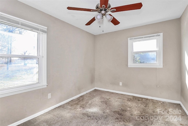 carpeted empty room with ceiling fan and plenty of natural light