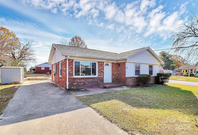 view of front of property with a front lawn and a storage shed