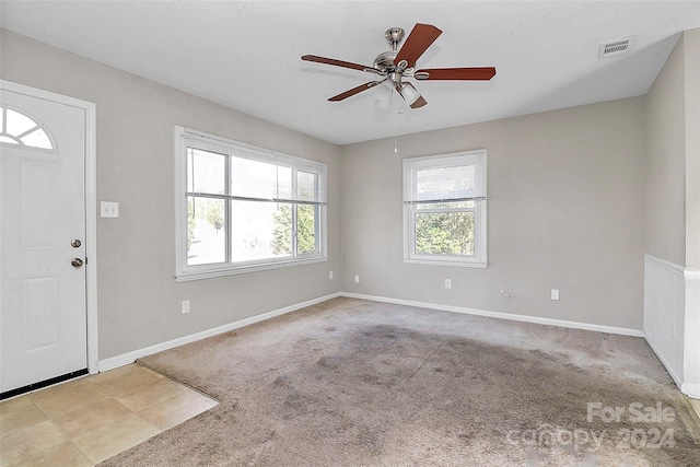 entryway with light colored carpet, a wealth of natural light, and ceiling fan