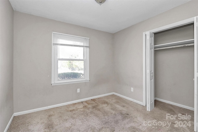 unfurnished bedroom with a closet, light colored carpet, and a textured ceiling