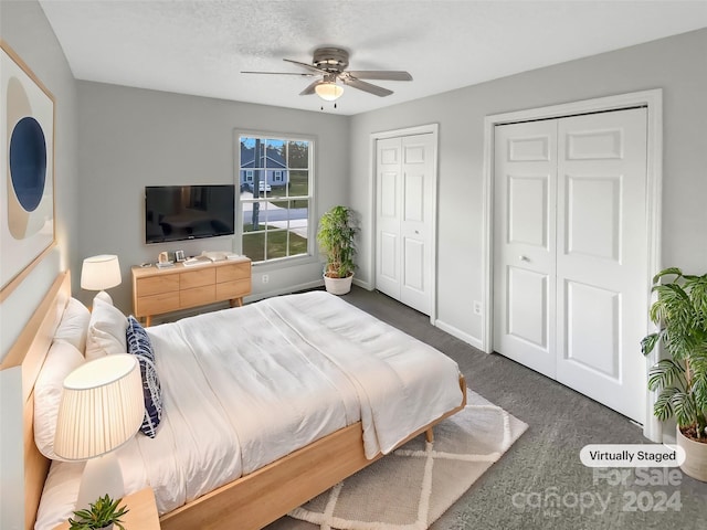 carpeted bedroom with ceiling fan, a textured ceiling, and multiple closets