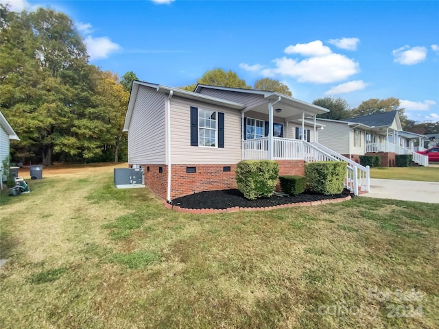 view of front of home featuring cooling unit, a front lawn, and covered porch