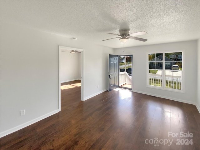 unfurnished room featuring dark hardwood / wood-style floors, ceiling fan, and a textured ceiling