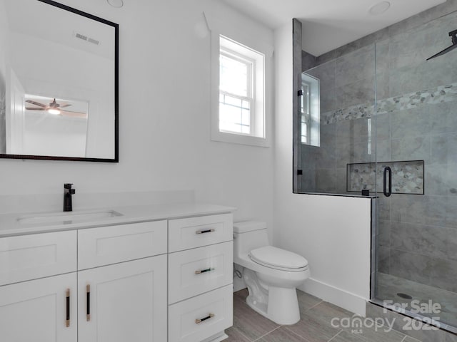 bathroom with ceiling fan, vanity, a shower with shower door, and toilet