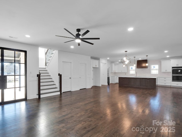 unfurnished living room with a wealth of natural light, ceiling fan, sink, and dark hardwood / wood-style floors