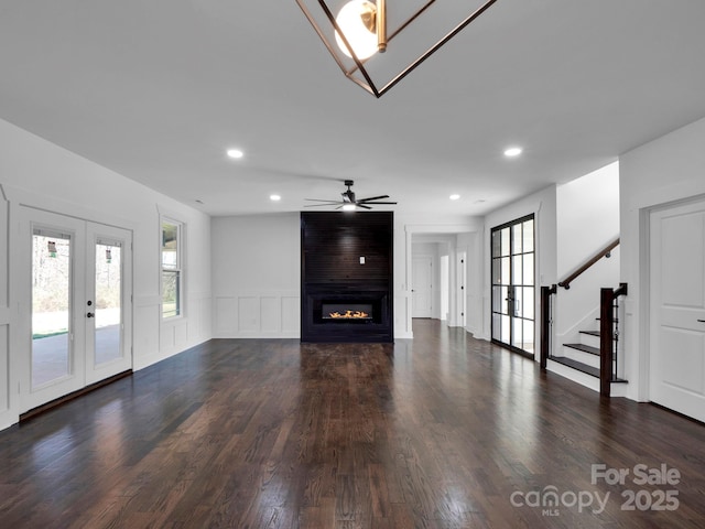 unfurnished living room featuring ceiling fan, dark hardwood / wood-style flooring, a fireplace, and french doors