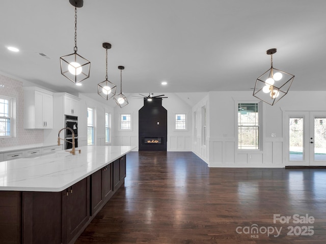 kitchen with double oven, dark hardwood / wood-style floors, white cabinetry, hanging light fixtures, and a large island