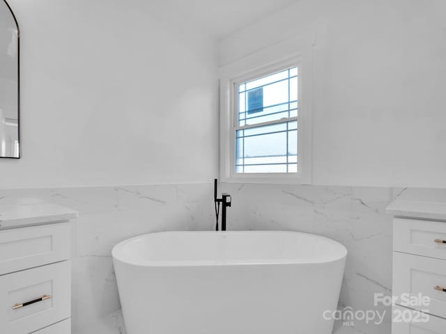 bathroom featuring a bathtub, vanity, and tile walls