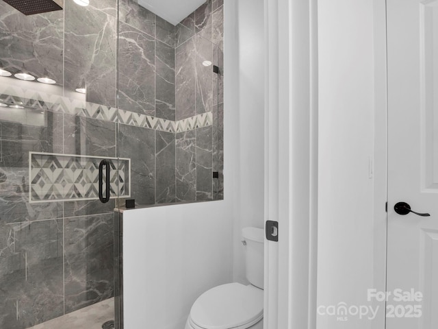 bathroom featuring a tile shower and toilet